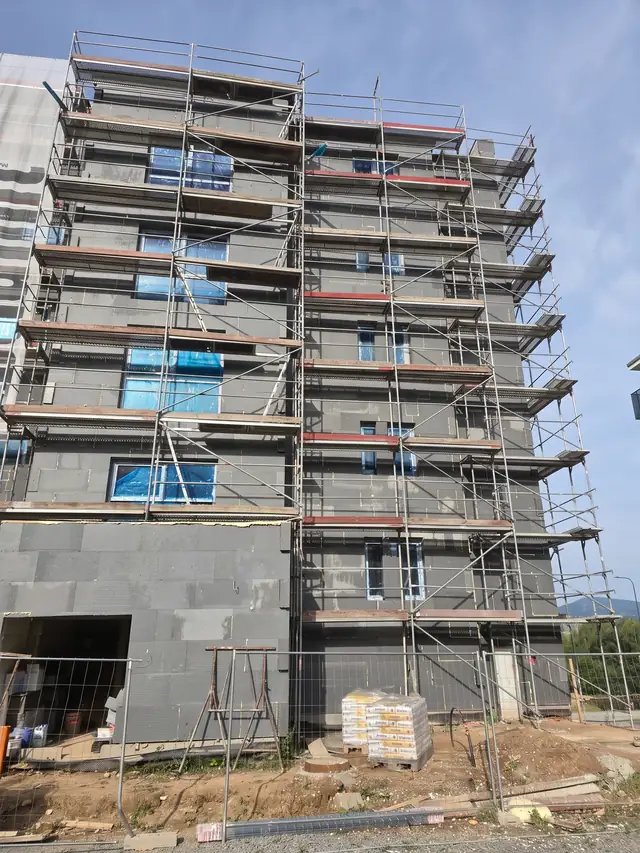 Wielokondygnacyjny blok z grafitowym styropianem na elewacji i rusztowaniem