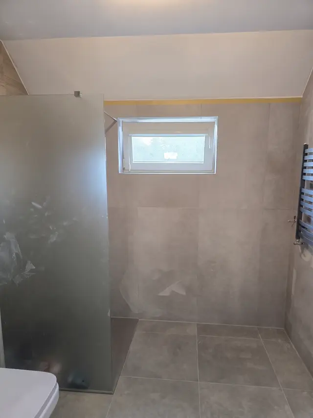 Prysznic walk-in na poddaszu z matową szybą, oknem i grzejnikiem