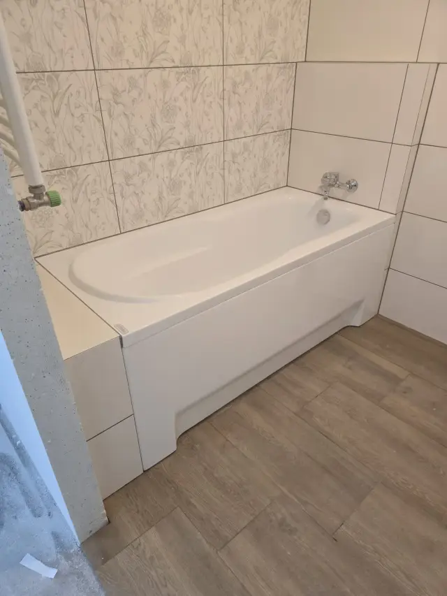 Wanna w zabudowie, płytki z roślinnym wzorem i podłoga z gresu drewnopodobnego