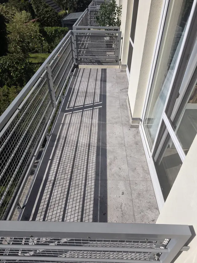 Balkon wyłożony gresem o betonowym wzorze, widok wzdłuż balustrady