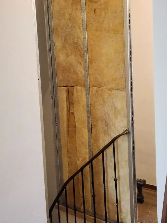 Wełna mineralna między profilami przy balustradzie schodów, bez wykończenia