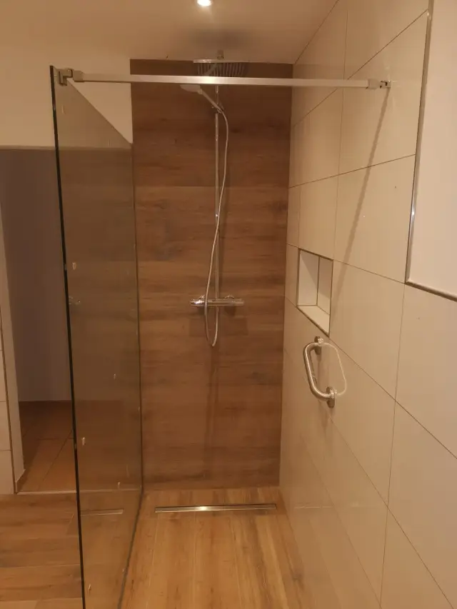 Prysznic walk-in ze szklaną ścianką, deszczownicą i liniowym odpływem, płytki imitujące drewno