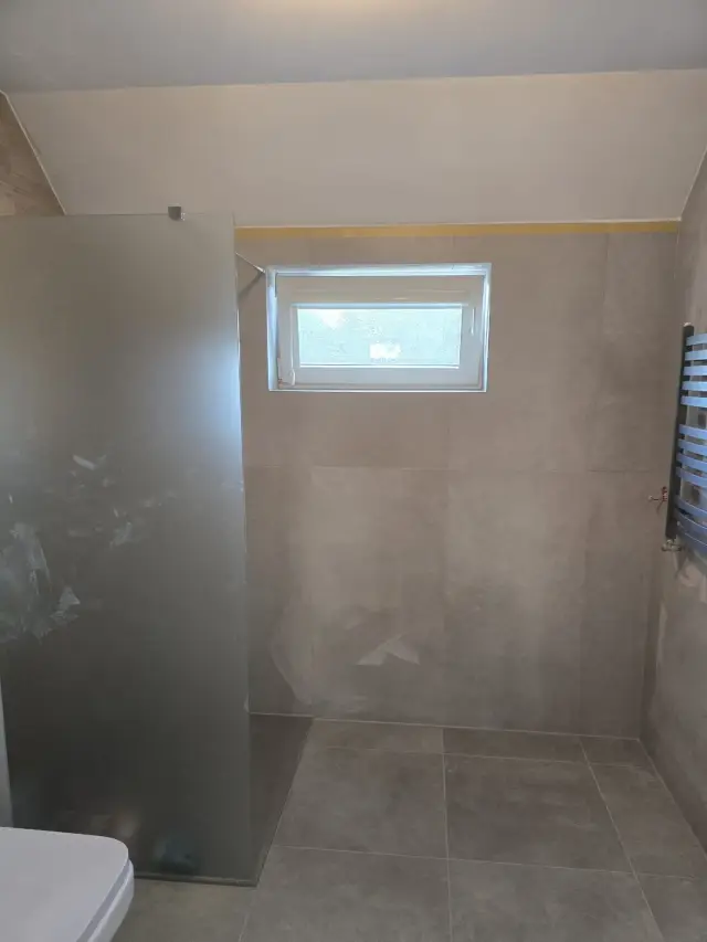 Prysznic walk-in na poddaszu z matową szybą, oknem i grzejnikiem