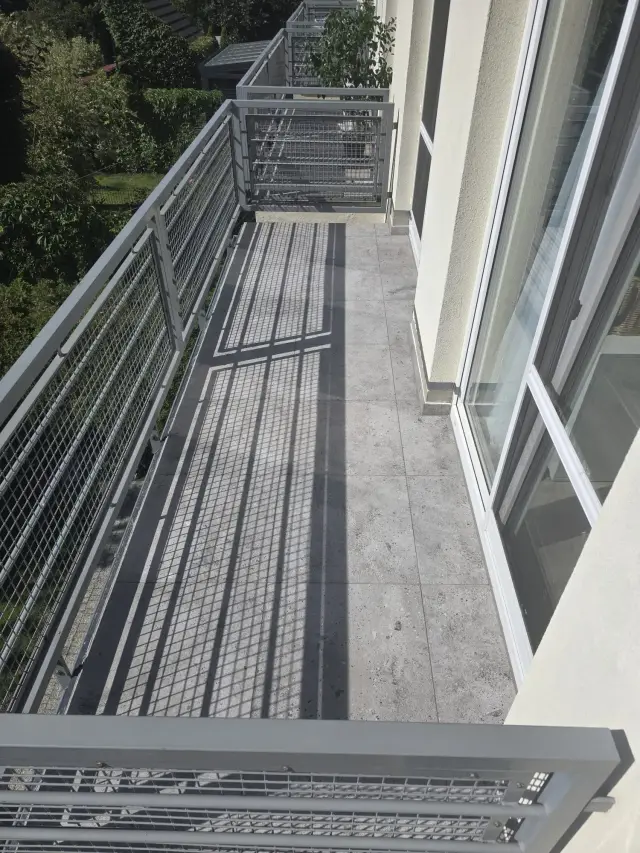Balkon wyłożony gresem o betonowym wzorze, widok wzdłuż balustrady