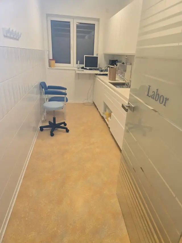 Pomieszczenie laboratorium z pomarańczową podłogą, zlewem i białymi szafkami